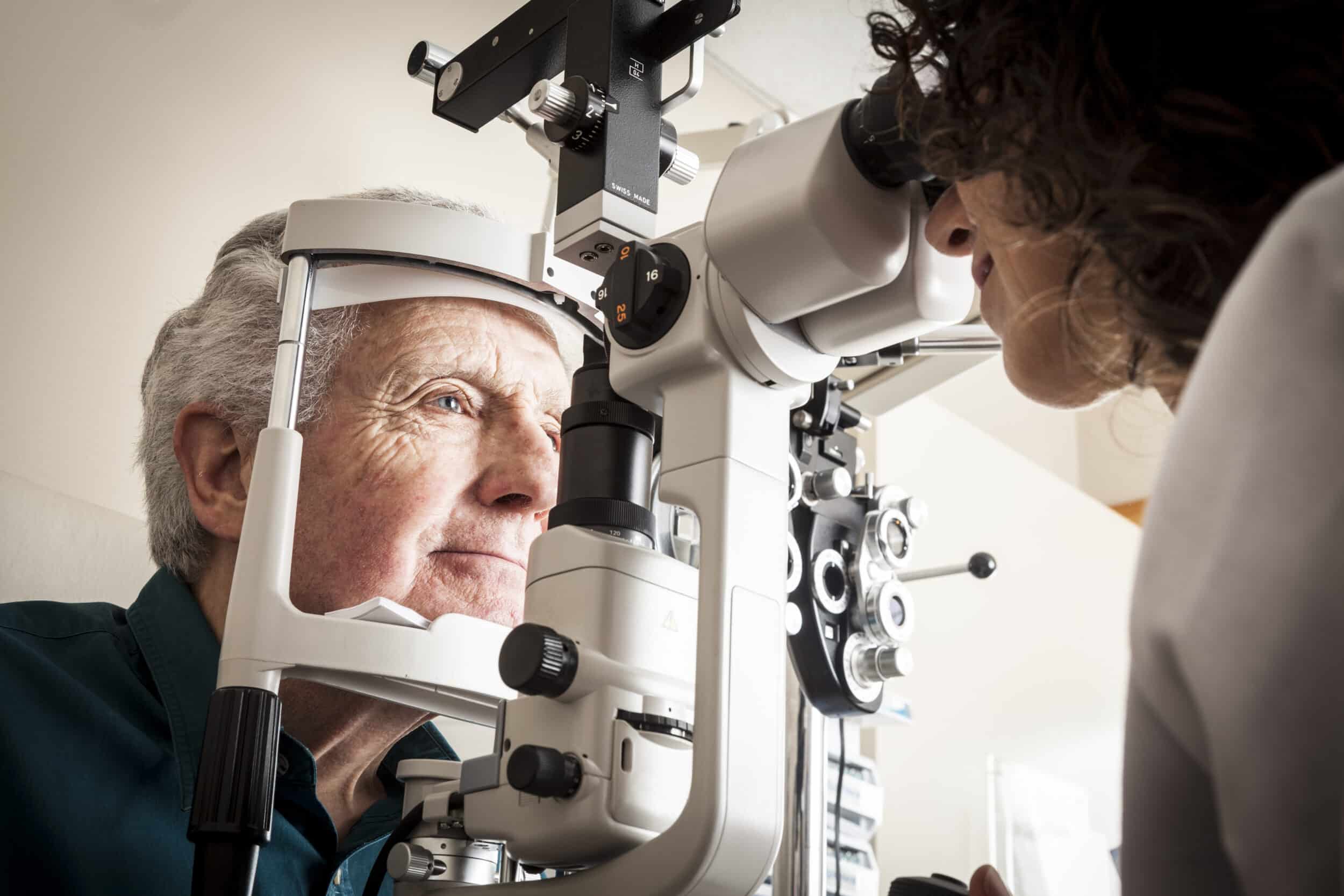 Optometrist giving eye exam to senior patient