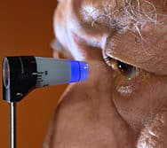 elderly patient with eye close up to glaucoma detection exam device