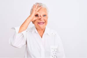 Senior grey-haired woman doing ok gesture with hand smiling