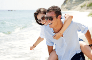 Happy young couple enjoying a solitary beach backriding