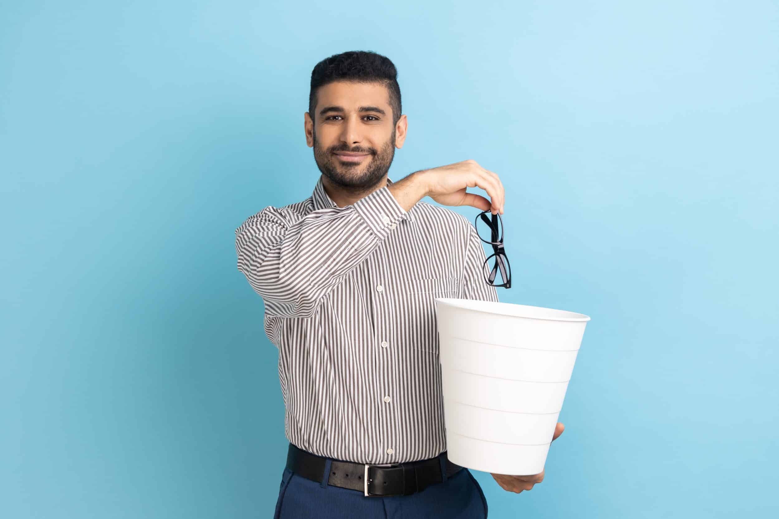 A man holding a trash can and throwing away his glasses after LASIK surgery