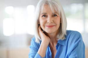 Senior woman smiles at camera with maintained eyesight after wet AMD treatment
