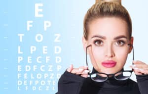 Young woman removing glasses near eye chart during ophthalmologist consultation, concept of vision testing and eye care