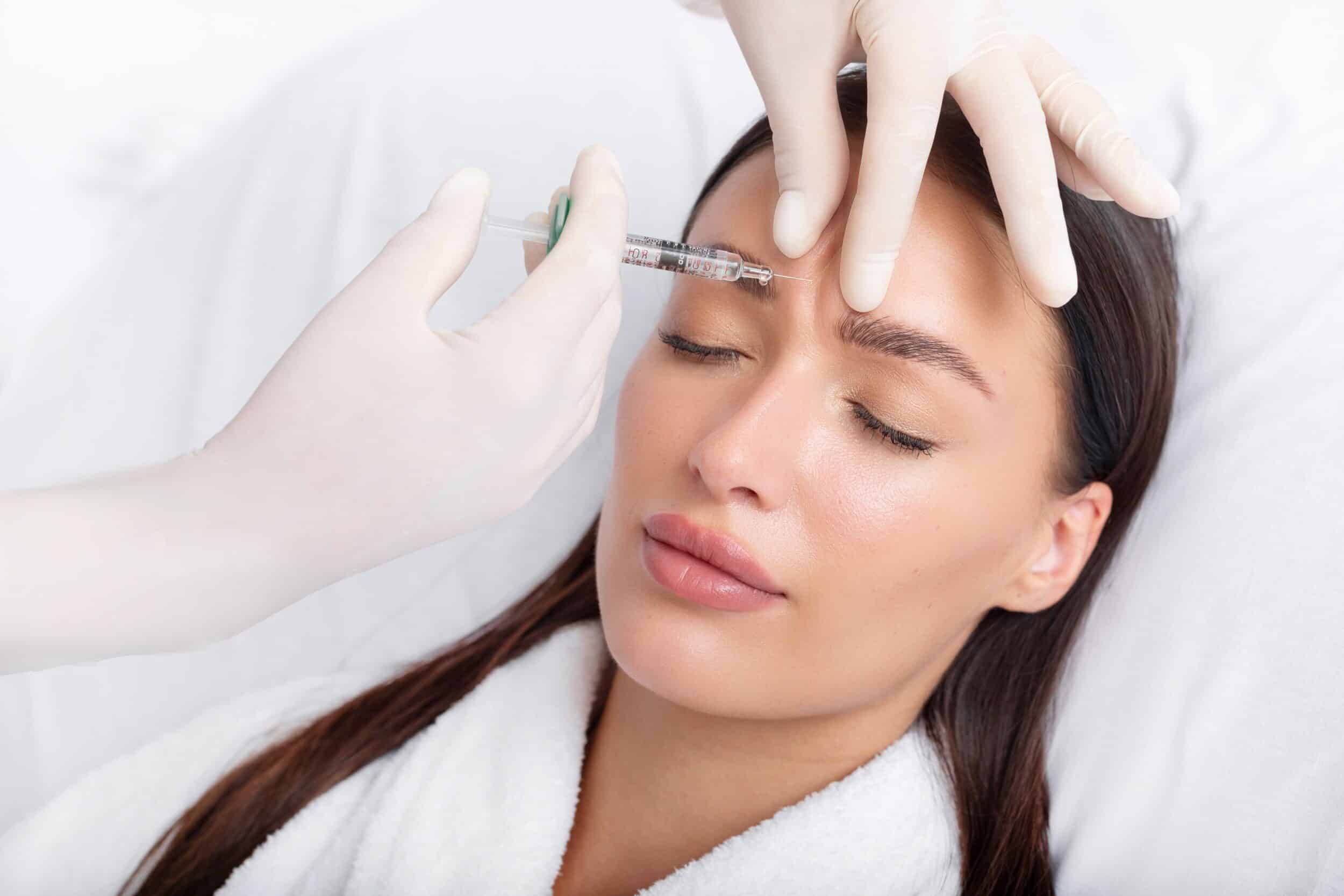 Woman receives Botox injection between her eyebrows