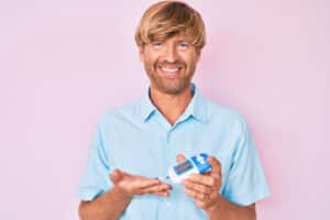 Shaggy haired blond man uses a glucose meter to check his blood sugar.